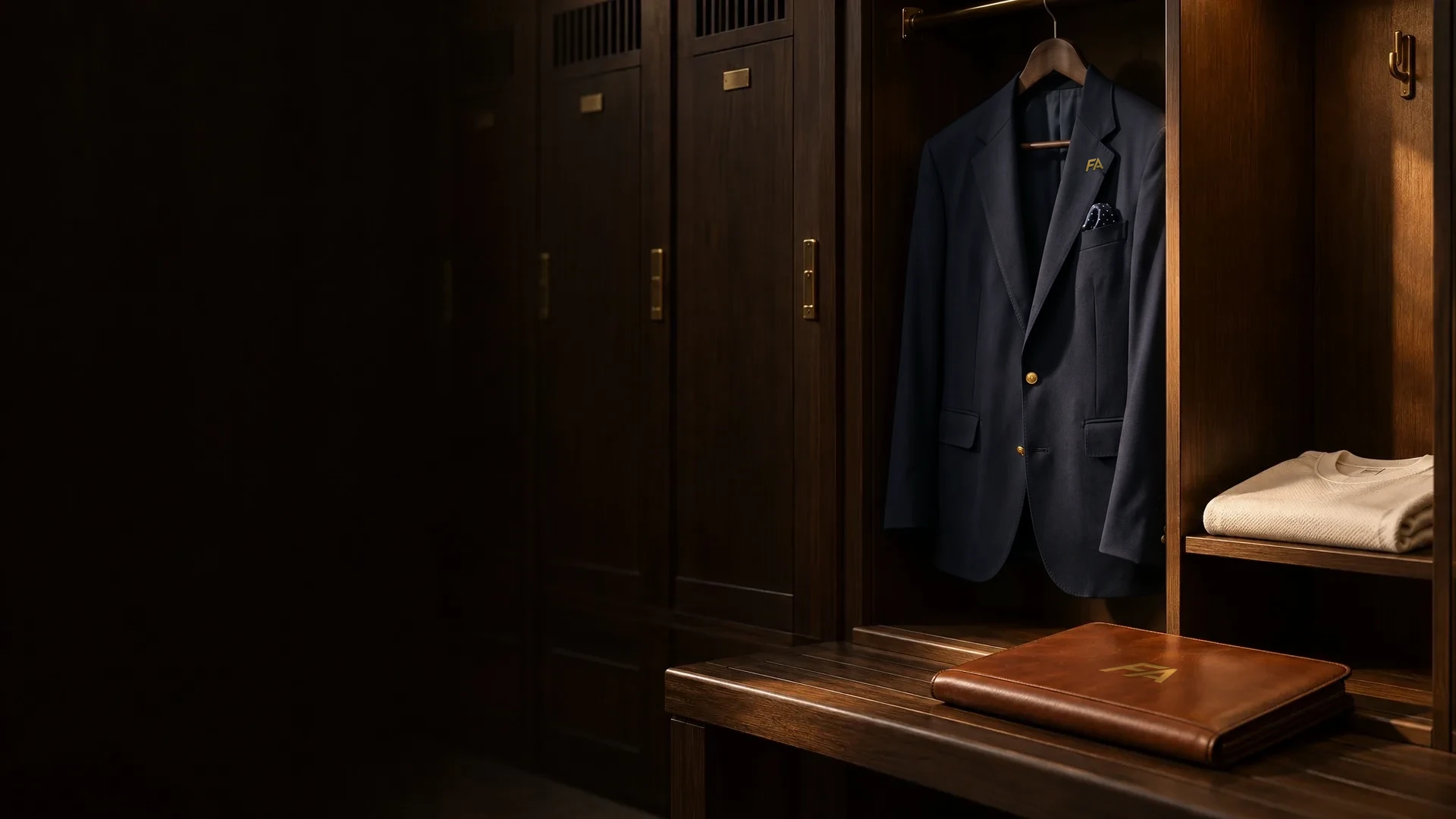 A navy blazer with a gold FA lapel pin hanging in a wood locker
